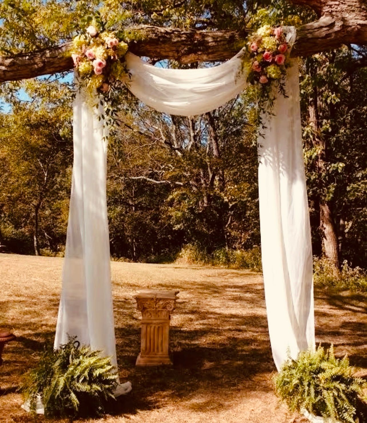 Arco de ceremonia con telas y flores al aire libre