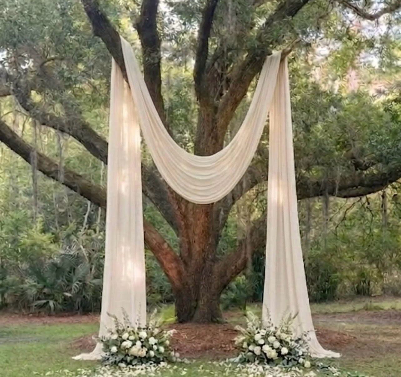 Ceremonia ambientada bajo un árbol con telas y flores